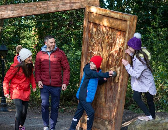 A family of four coming walking through the wardrobe in Narnia at Kilbroney Park.