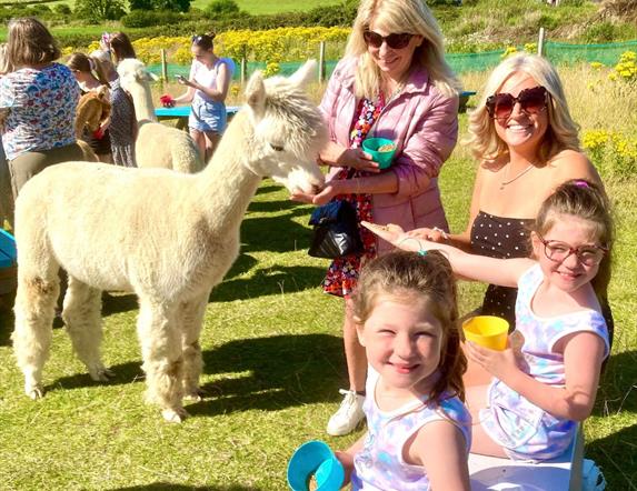 Ladies and children feeding Alpaca