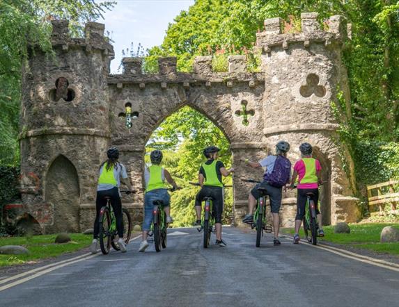 Image of people cycling bikes into the entrance of Tollymore Forest Park