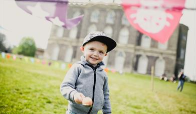 Young boy holding egg and spoon outside Castle Ward Mansion