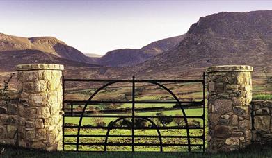 Iron gate with stone pillars and view of Mountains