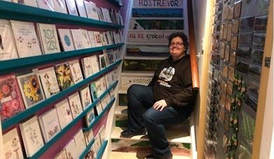 Pictured is Belinda Cullen sitting on the stair, owner of Good Craic Gifts and Souvenirs in Rostrevor.  On the bottom step Belinda has written 'there