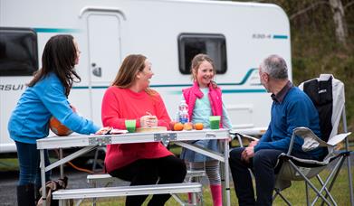 Family at table outside caravan
