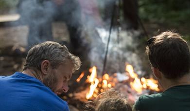 Father and Children outdoors, sat in front of a fire