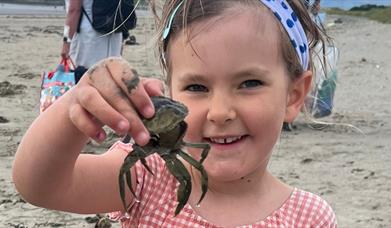 Child holding a crab up close to the camera