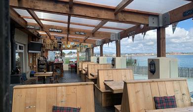 Outside dining area of The Harbour House Inn with wooden benches overlooking the stunning sea