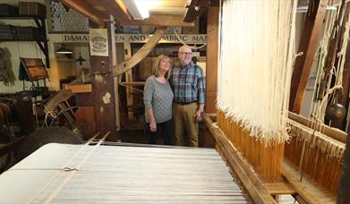 Couple viewing a linen weaving loom.