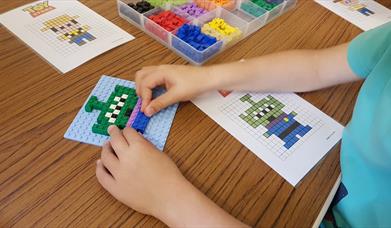Close up photo of a child's hands constructing a toy model from Lego bricks