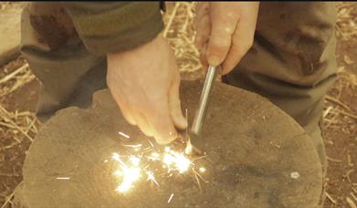 Bushcraft. Hands lighting fire on stone