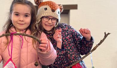 Two girls proudly holding their craft they made with twigs at the Forest Activities event.