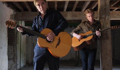 The 4 of Us - two people standing playing guitars.