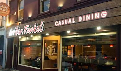 picture showing the front of resturantlit up at night time.