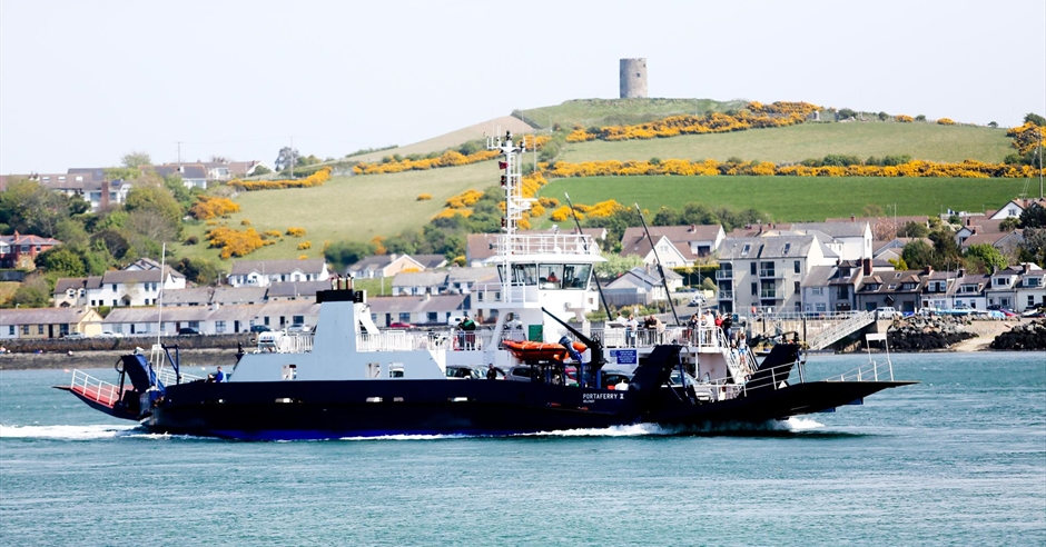 The Portaferry ferry crossing the narrow section of Strangford Lough, Northern Ireland, carrying cars and passengers with calm waters and green shores on either side.