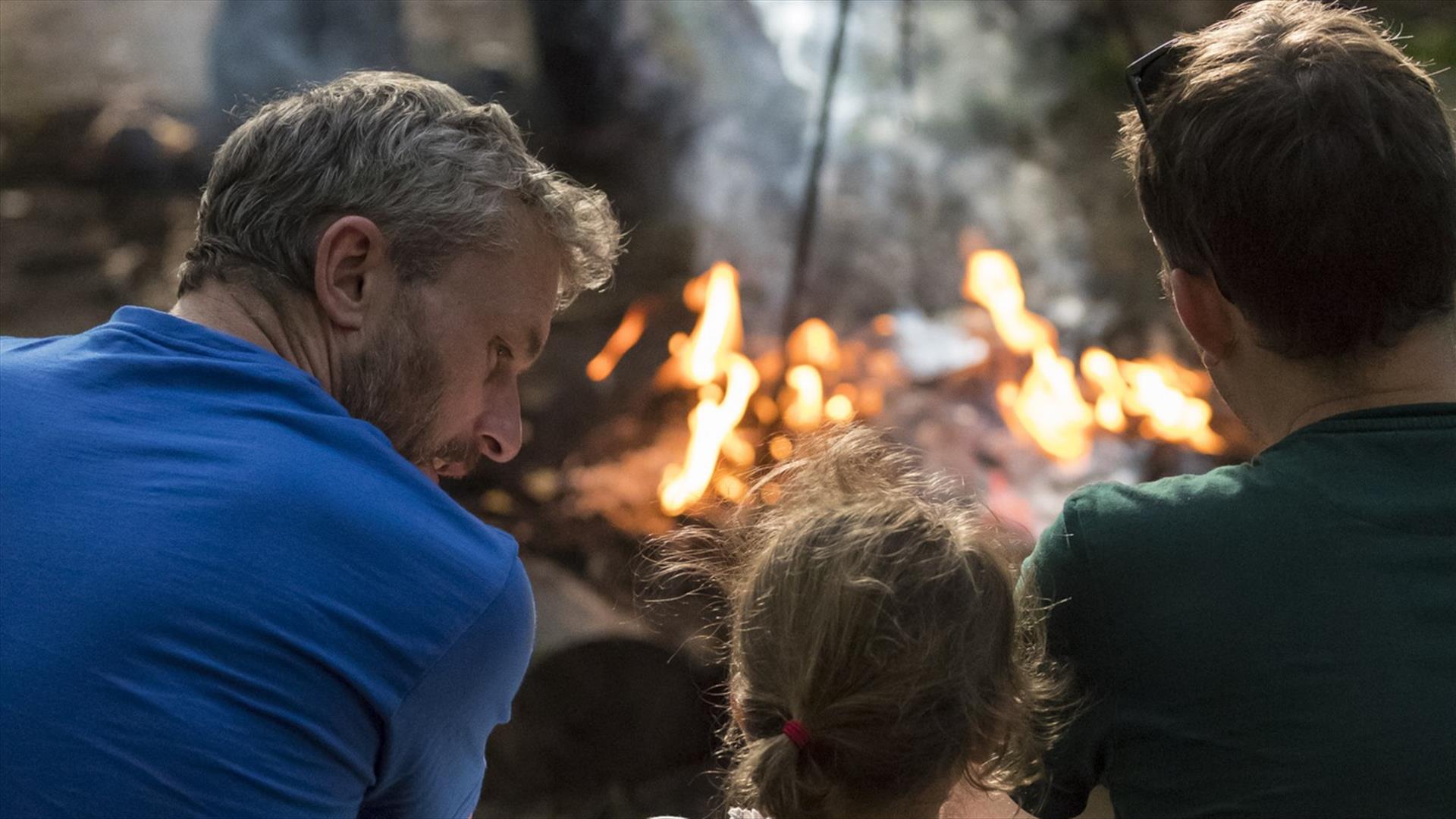 Father and Children outdoors, sat in front of a fire