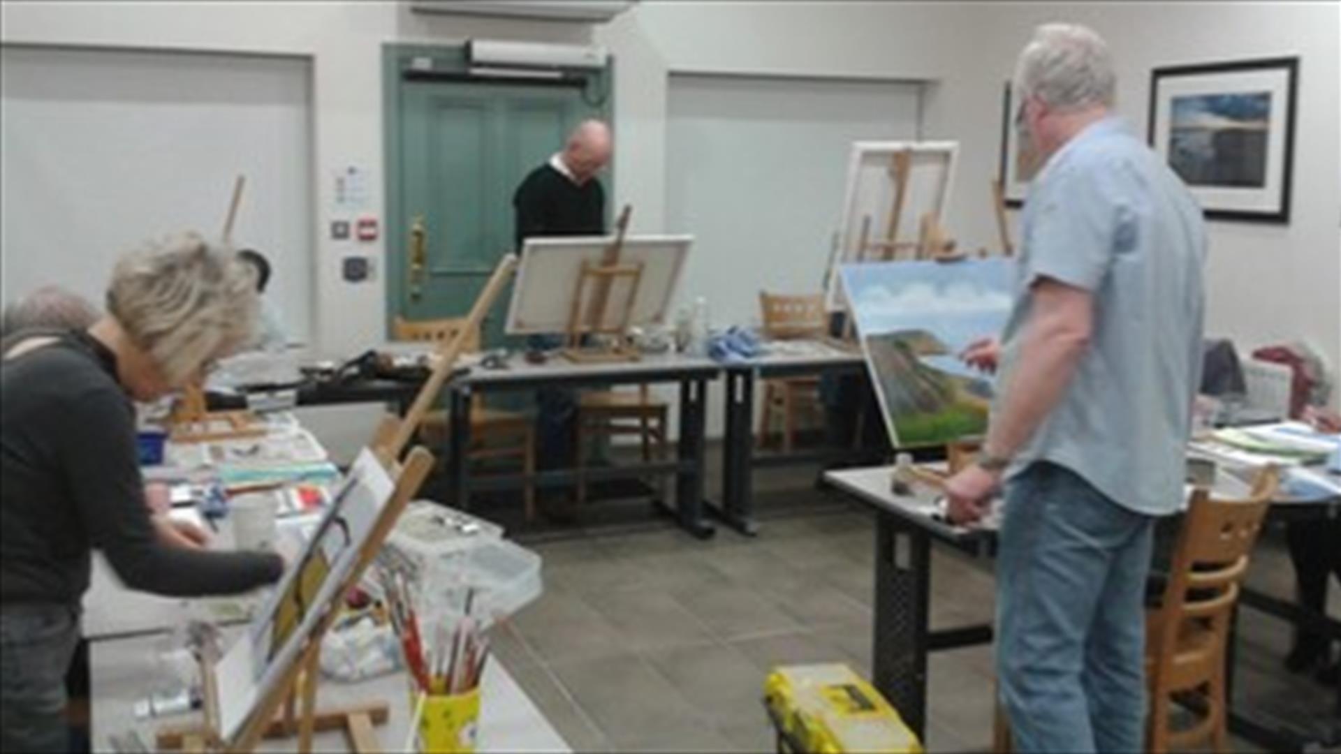A photograph of Martin McParland painting on a canvas in Down Arts Centre whilst leading an acrylic painting course.