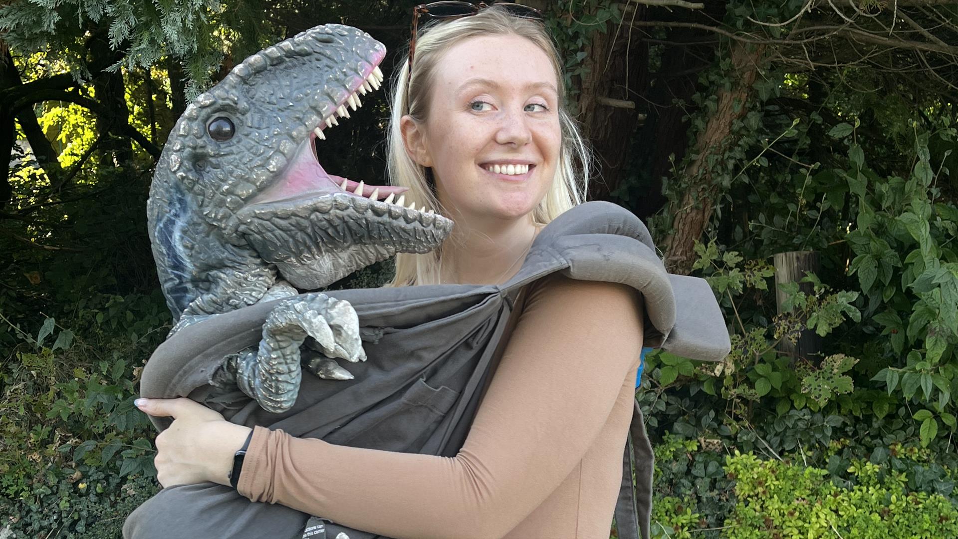 A dino being cuddled in a sling