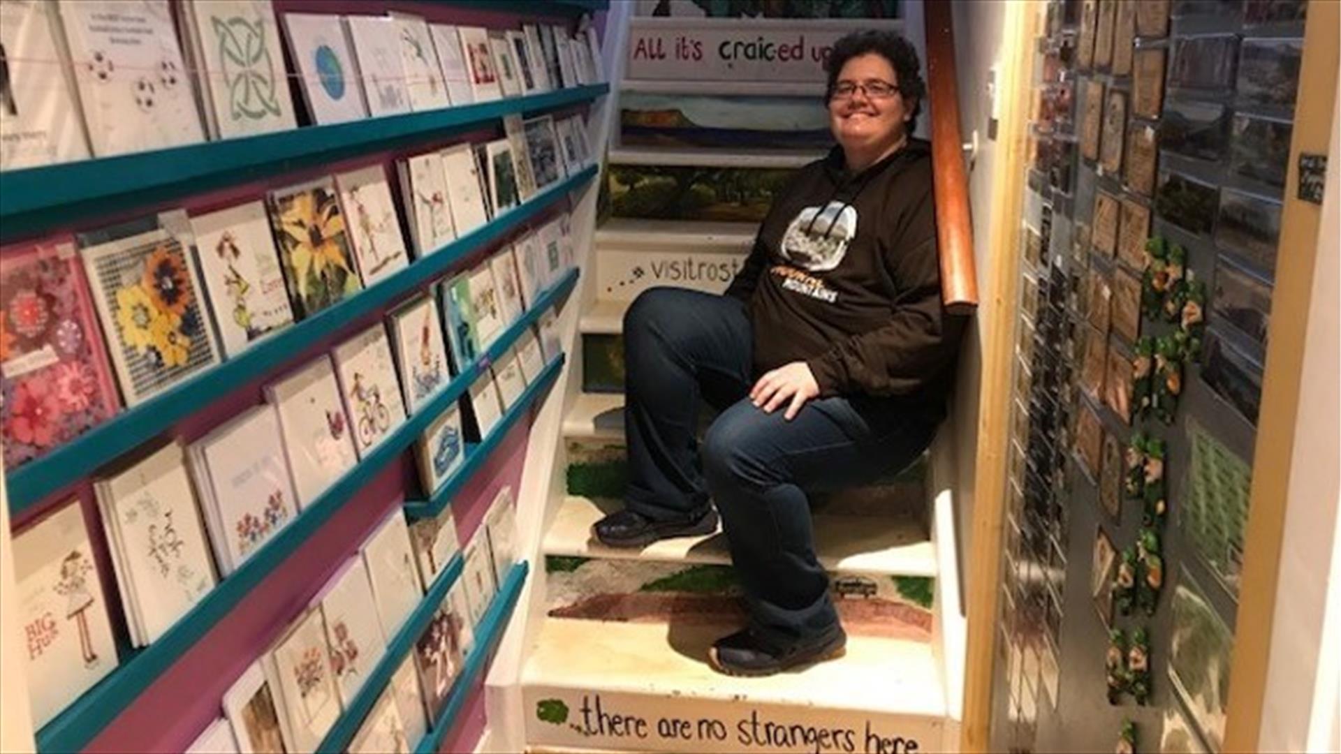 Pictured is Belinda Cullen sitting on the stair, owner of Good Craic Gifts and Souvenirs in Rostrevor.  On the bottom step Belinda has written 'there