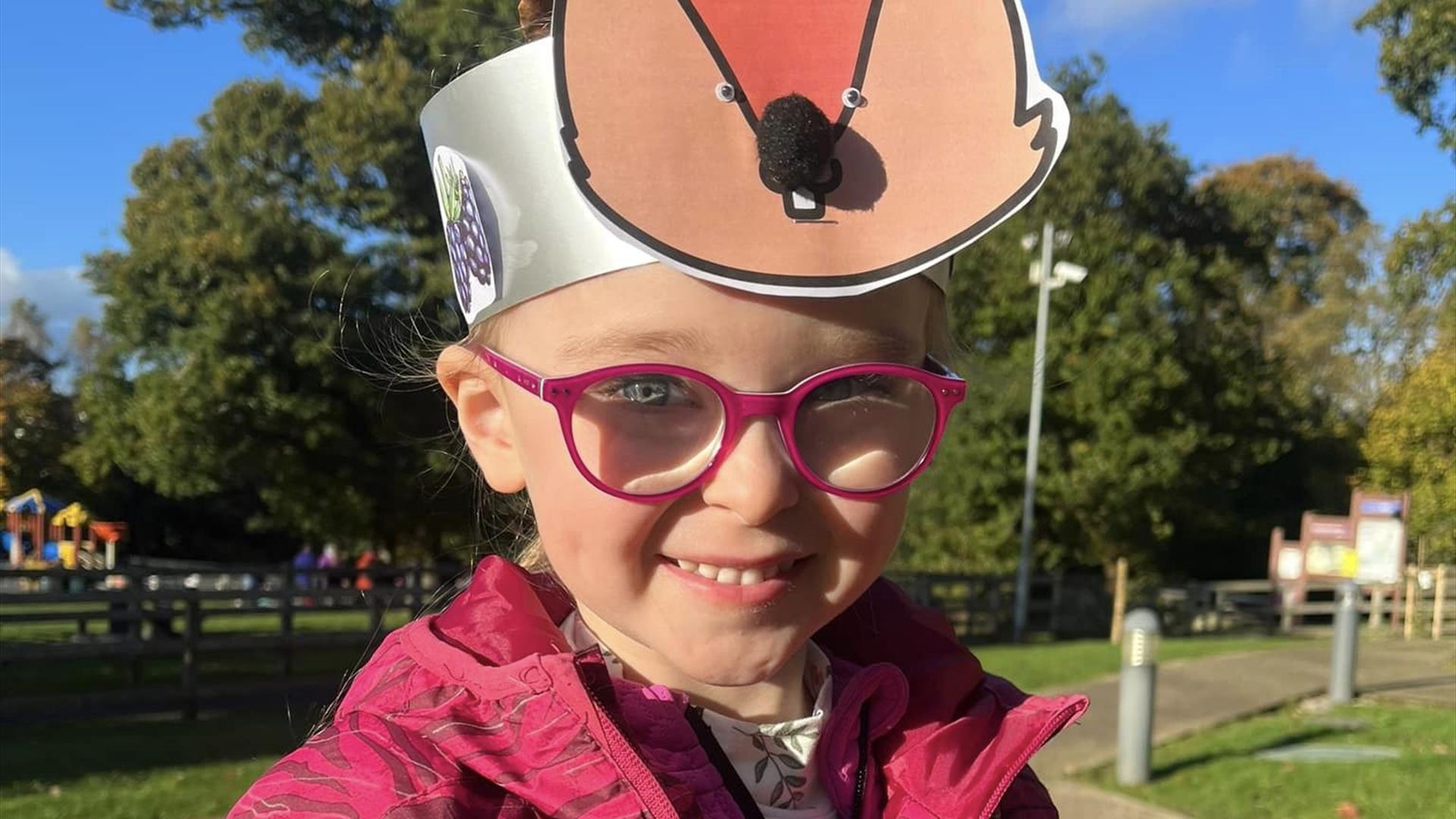 Child with Squirrel crafted paper hat smiling in forest park