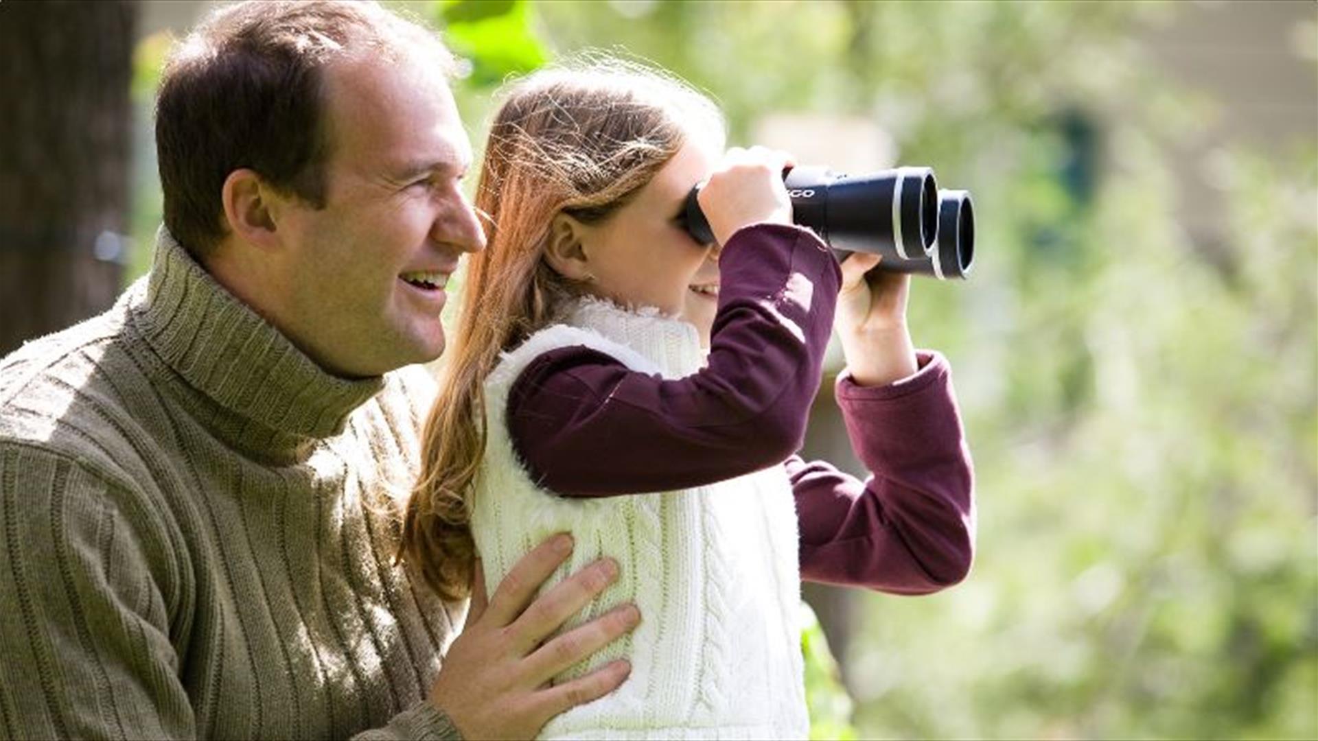 Two people bird watching in Castlewellan Forest Park. The child is looking through binoculars.
