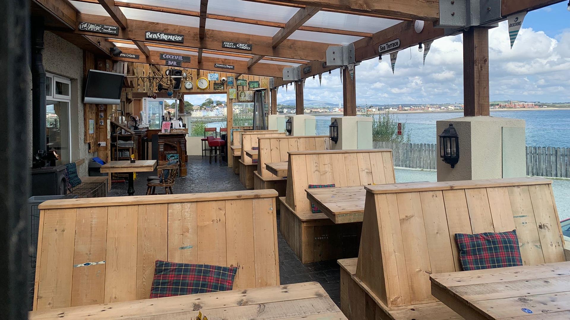 Outside dining area of The Harbour House Inn with wooden benches overlooking the stunning sea