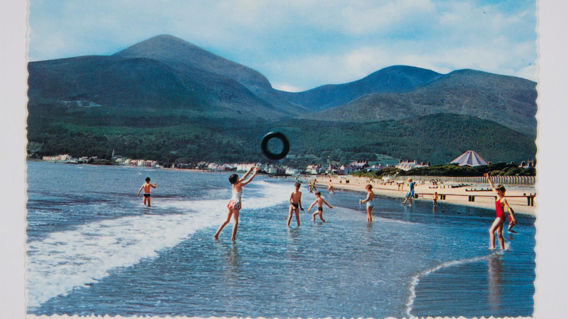 Children play on Newcastle beach with the Mourne Mountains behind them