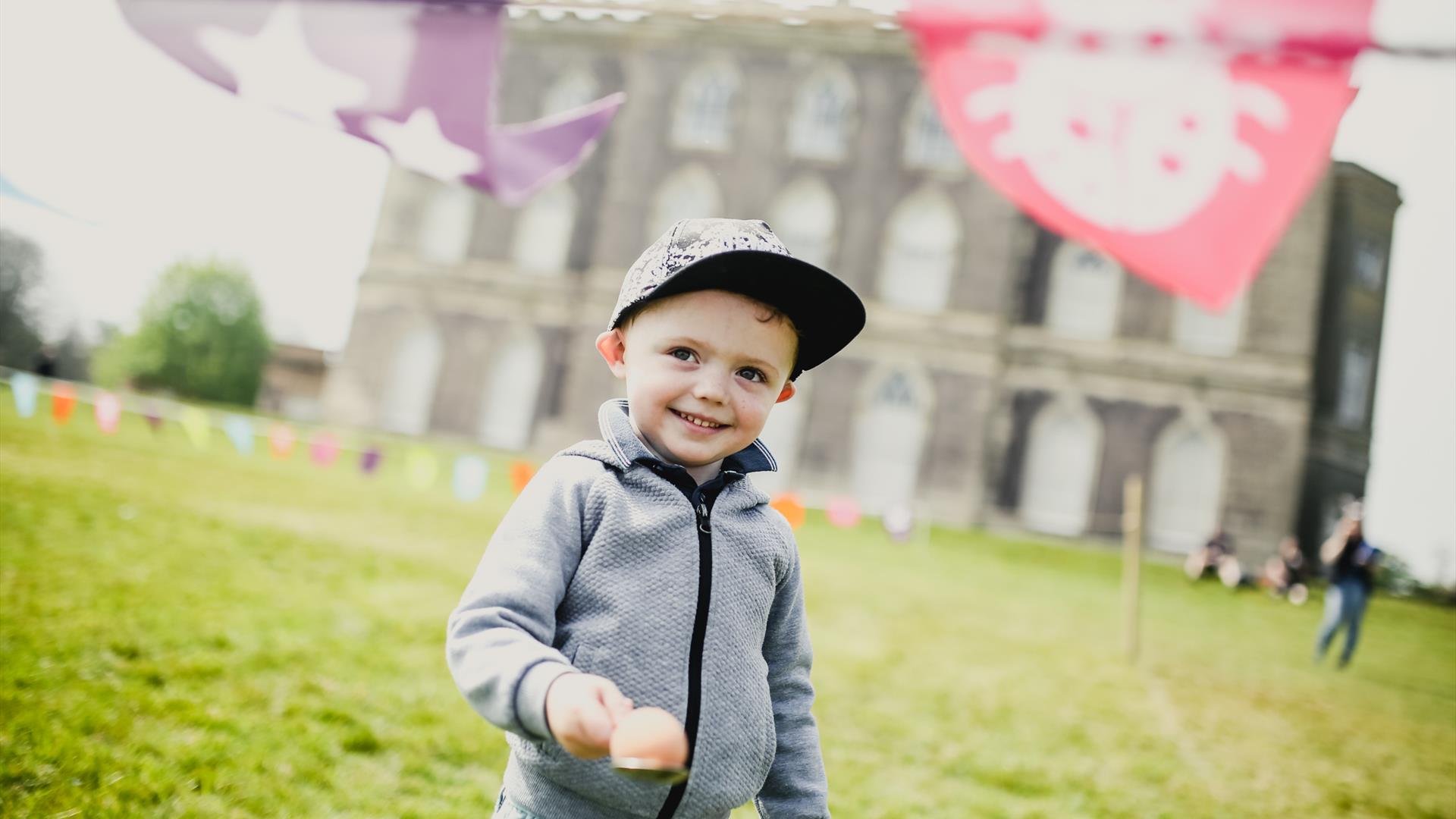 Young boy holding egg and spoon outside Castle Ward Mansion