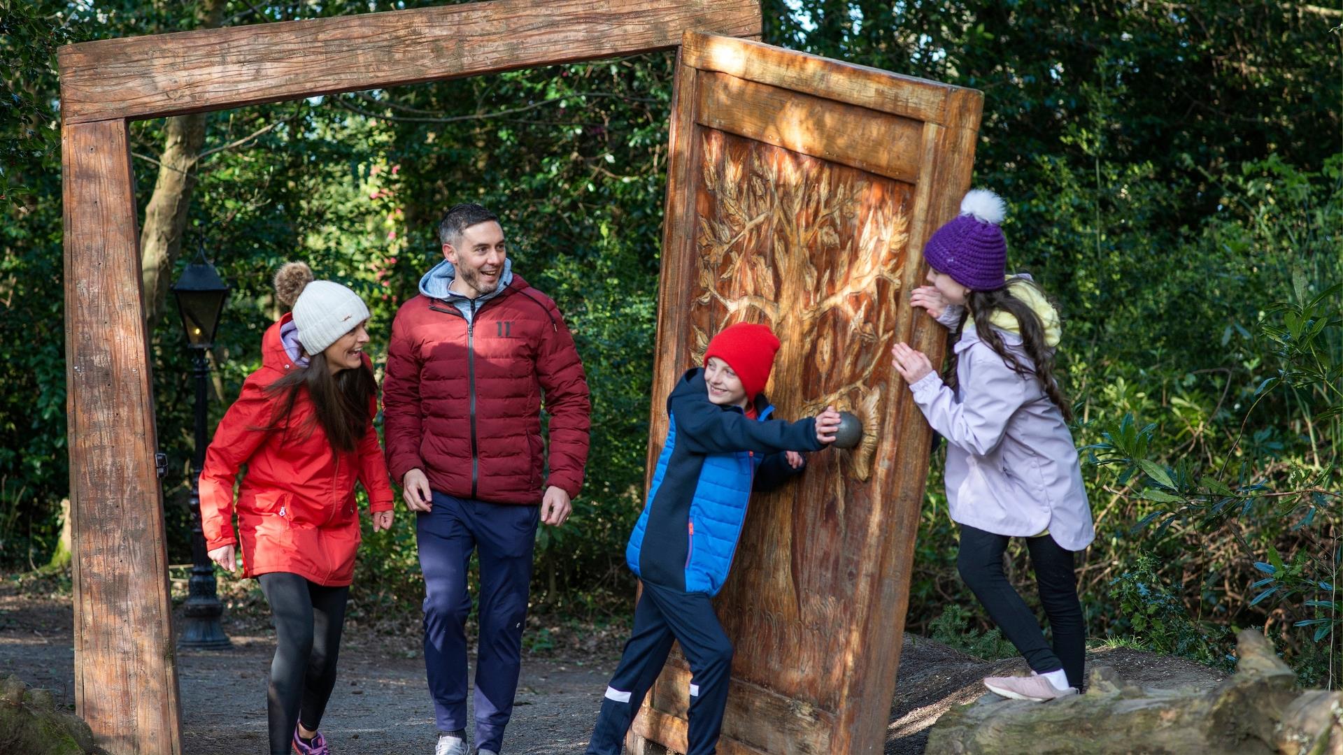 A family of four coming walking through the wardrobe in Narnia at Kilbroney Park.