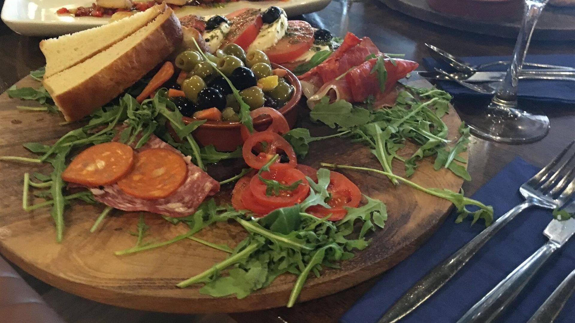 Wooden platter with salad, olives, ham