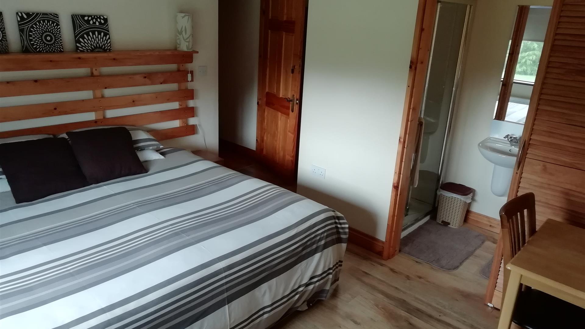 An image of a bedroom in Arley House, large bed with a grey/white striped duvet cover, with ensuite.