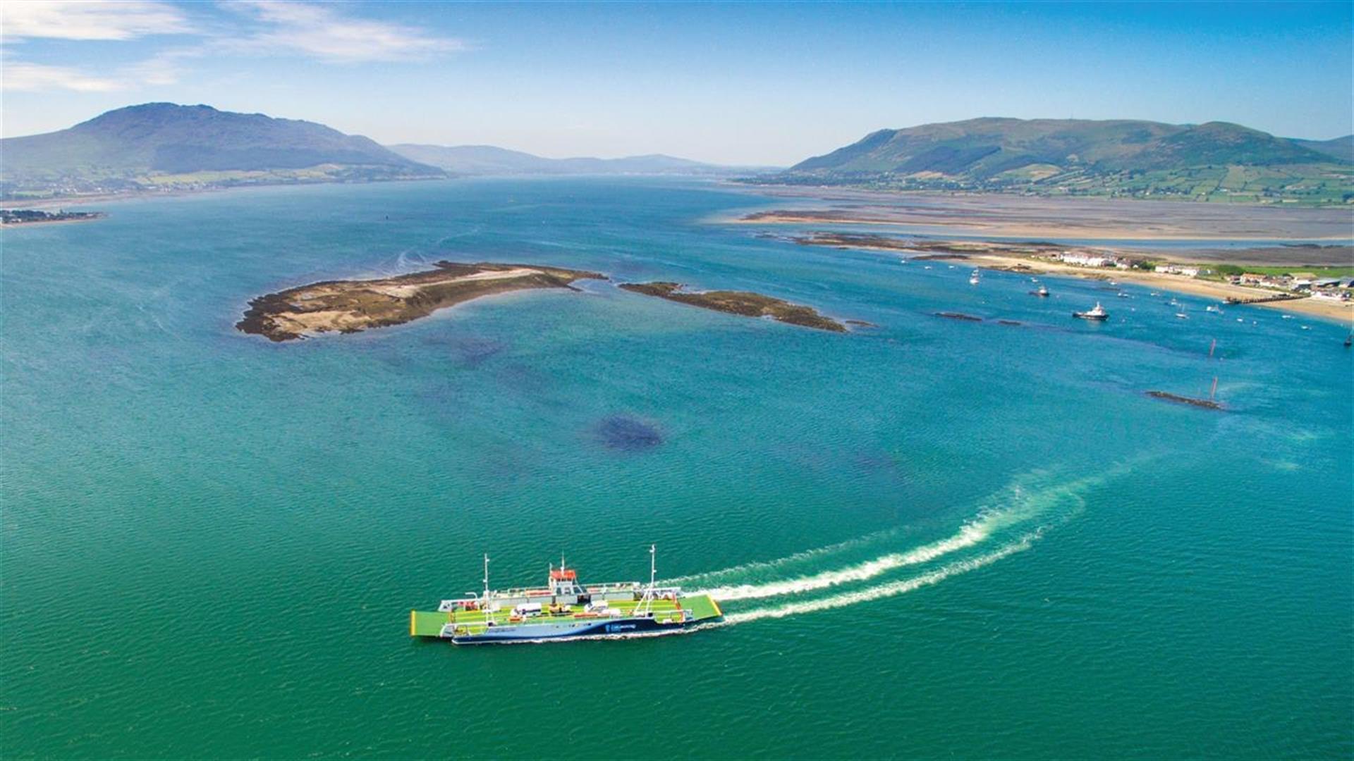 The Carlingford Lough Ferry crossing the water between Warrenpoint, Northern Ireland, and Omeath, Republic of Ireland, with hills in the background.