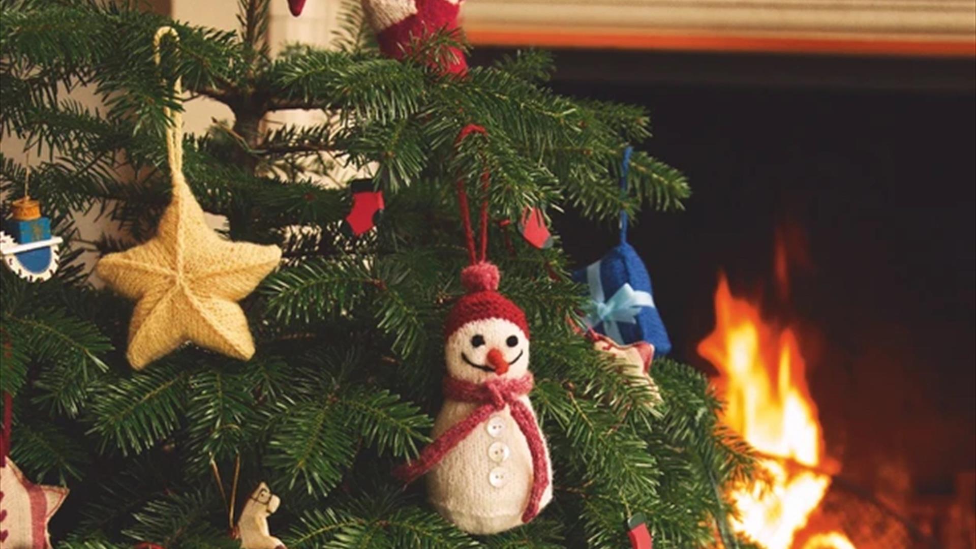 Picture displaying a knitted snowman and a star hanging on a Christmas tree.