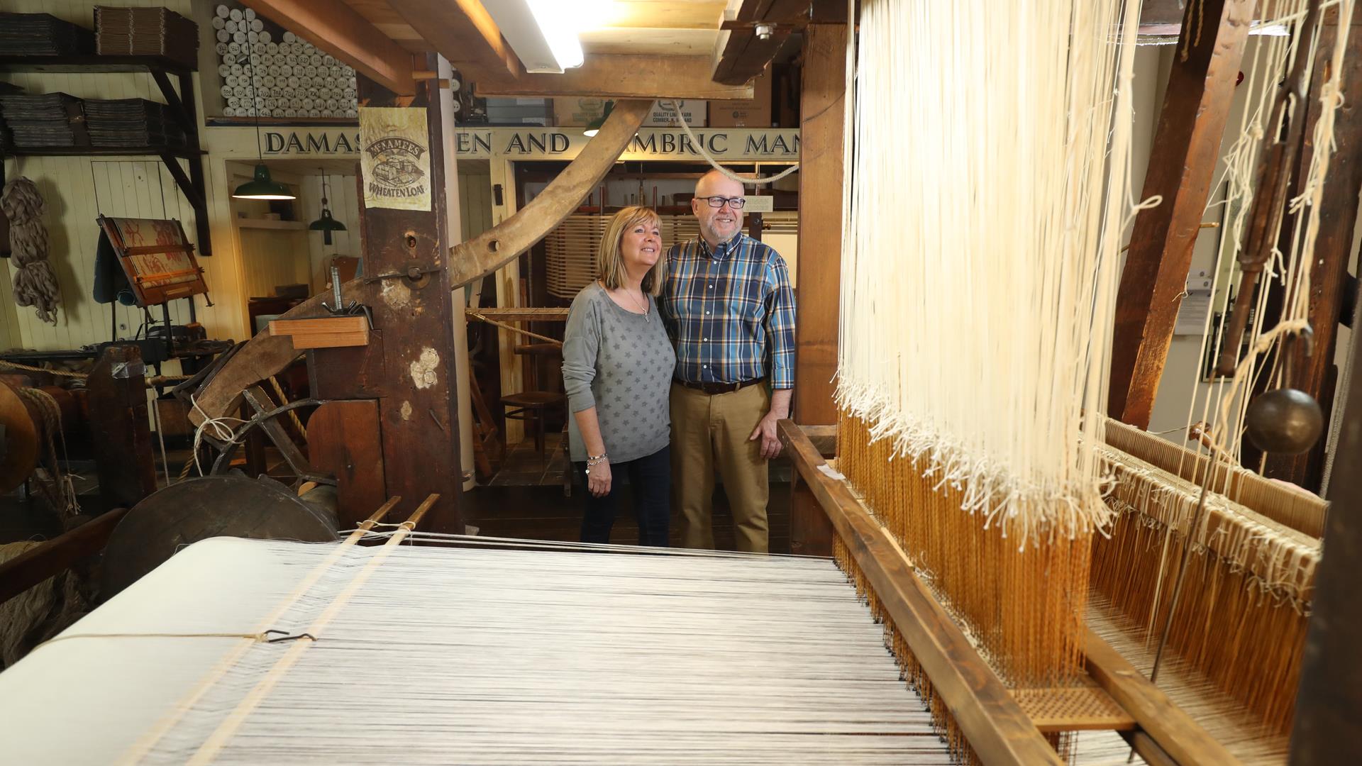 Couple viewing a linen weaving loom.