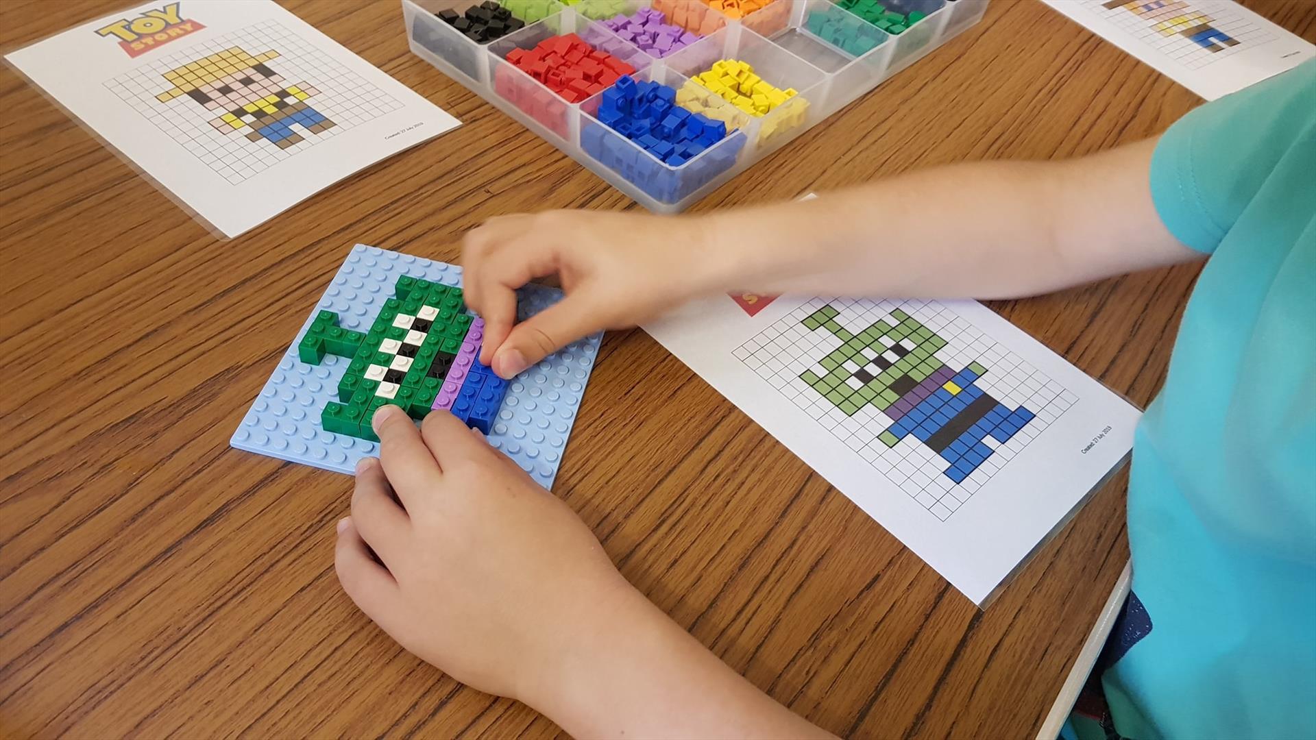 Close up photo of a child's hands constructing a toy model from Lego bricks