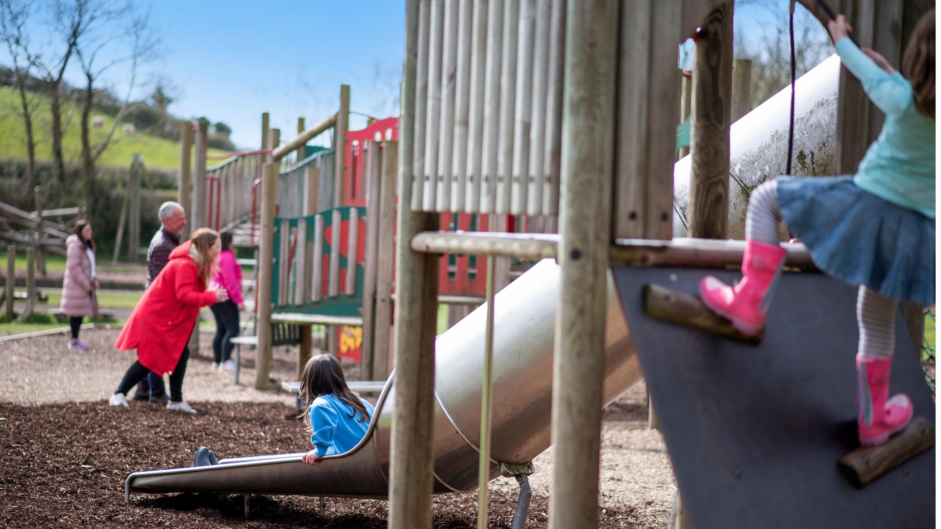 Child climbing and another on a slide in the play park, at Delamont Country Park.