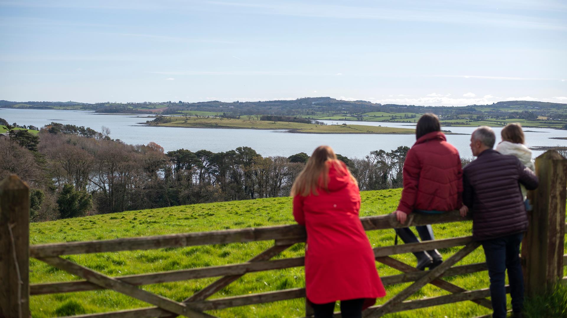 Family standing over a gate looking at the fabulous view of the Islands on Strangford Lough, from Grey Point Lookout at Delamont Country Park.