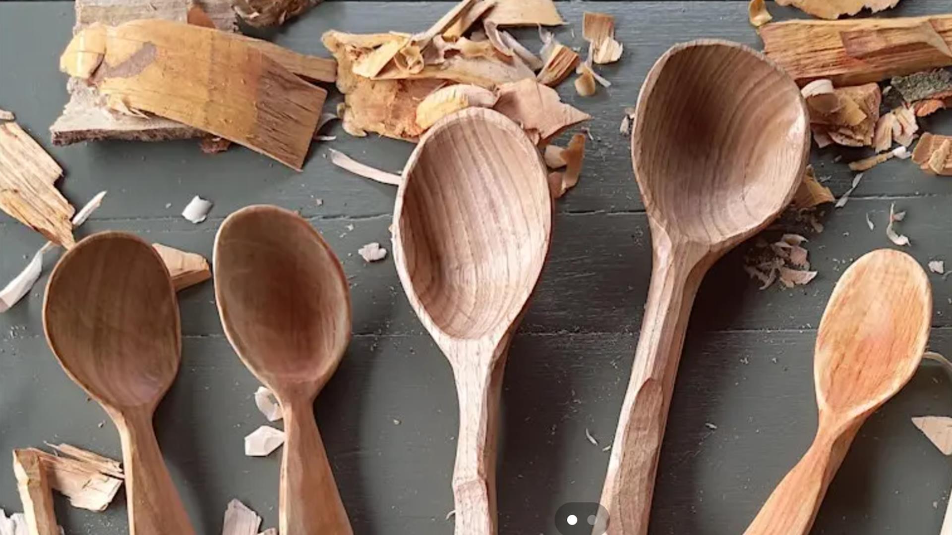 Five wooden spoons sittin on a table with some wood carvings surrounding. Crafting a cooking spoon to celebrate Celtic spring event.