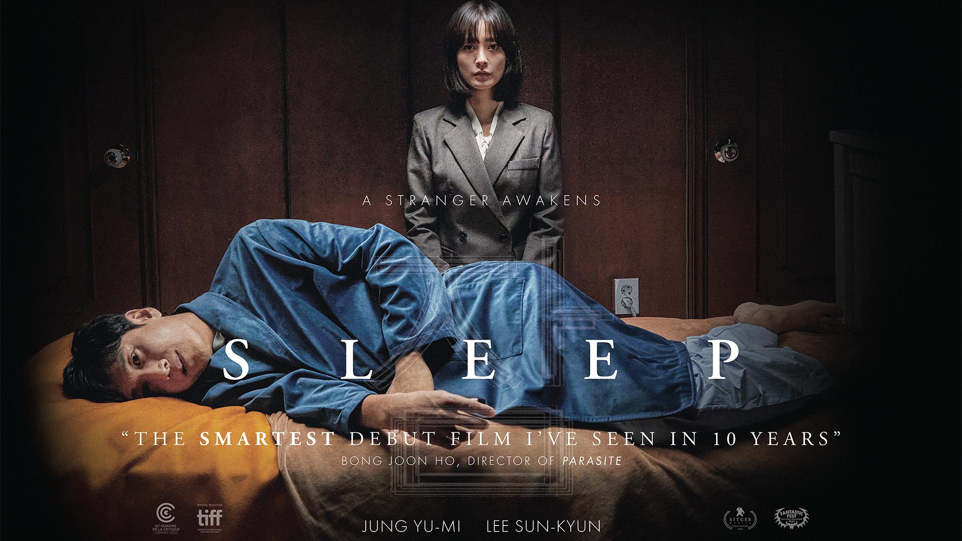 A man lies in a sleeping position, looking forward in horror, while woman stands over him looking directly at the camera.