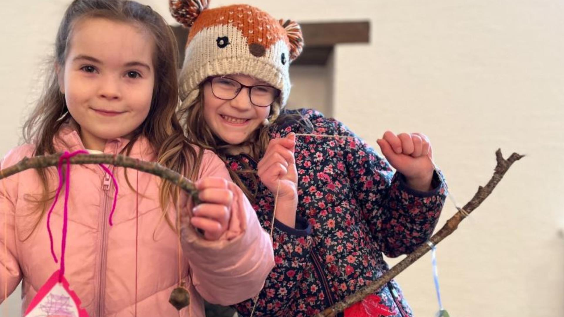 Two girls proudly holding their craft they made with twigs at the Forest Activities event.