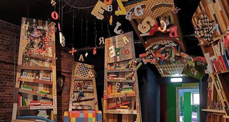 Interior play area at The Imaginarium. Black and white tiled floor with colourful furniture and soft blocks.