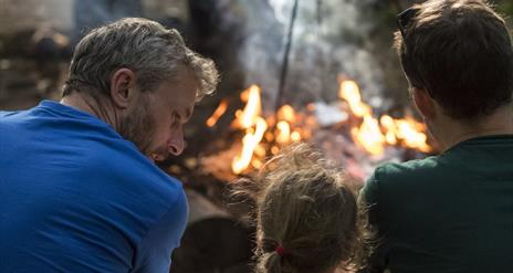 Father and Children outdoors, sat in front of a fire