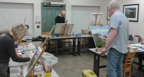 A photograph of Martin McParland painting on a canvas in Down Arts Centre whilst leading an acrylic painting course.