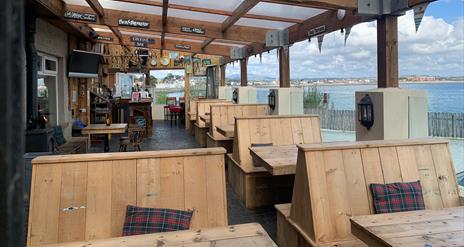 Outside dining area of The Harbour House Inn with wooden benches overlooking the stunning sea