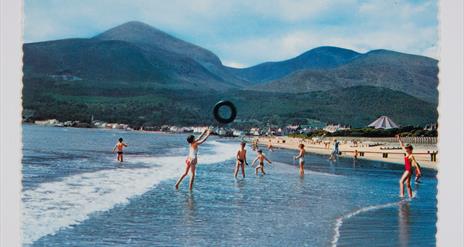 Children play on Newcastle beach with the Mourne Mountains behind them