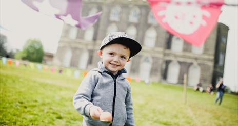 Young boy holding egg and spoon outside Castle Ward Mansion