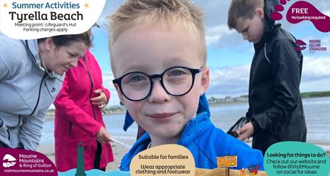 Upclose picture of a boy enjoying beach activities with three people in the background exploring a rock pool.