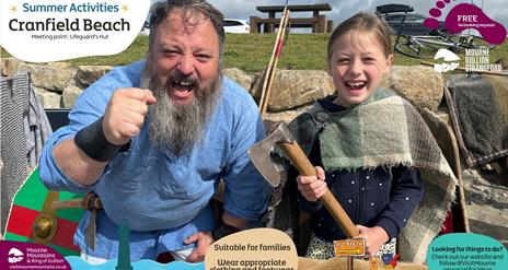 A viking and a child enjoying summer activities at Cranfield Beach.
