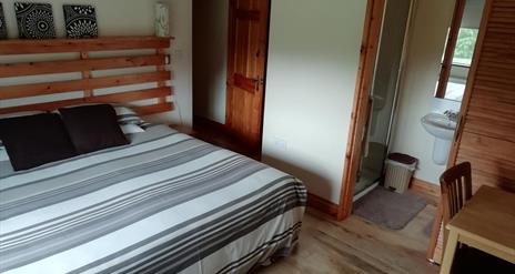 An image of a bedroom in Arley House, large bed with a grey/white striped duvet cover, with ensuite.