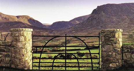 Iron gate with stone pillars and view of Mountains