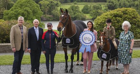 show organisers stand in front of castlewellan lake with a pony and a horse