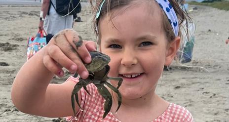 Child holding a crab up close to the camera